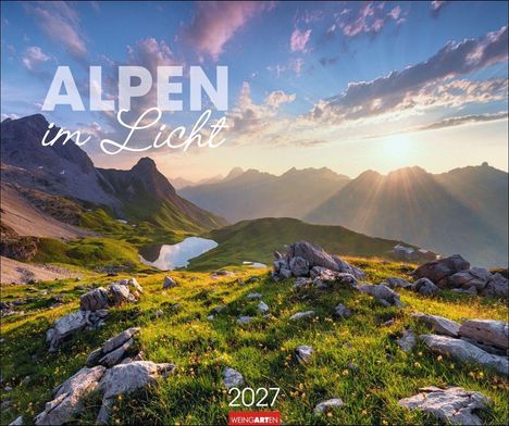 "ALPEN im Licht" und "2027" stehen über einer Berglandschaft bei Sonnenaufgang mit grünen Wiesen und einem klaren See.