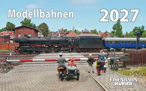 Modellbahnen 2027. Eine Dampflok auf Gleisen, beobachtet von Menschen. Ländlicher Hintergrund mit Gebäuden.