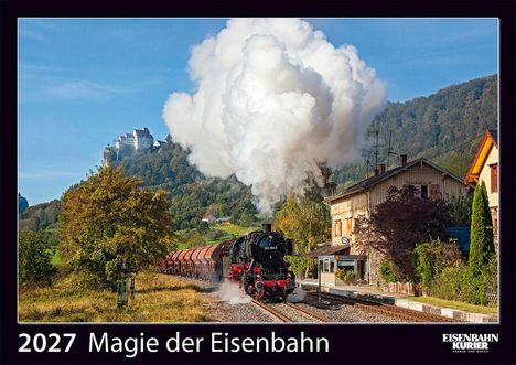 2027 Magie der Eisenbahn. Eine alte Dampflok fährt an einem Gebäude vorbei, Berge im Hintergrund.