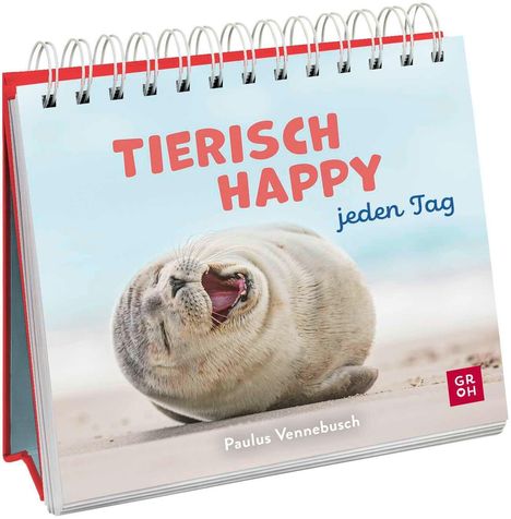 „TIERISCH HAPPY jeden Tag“ steht oben. Ein lächelndes Seehundjunges rollt lachend im Sand. Unten: „Paulus Vennebusch“.