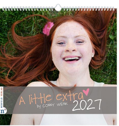 „A little extra by CONNY WENK 2027“ ist in verspielter Schrift zu sehen. Eine Person mit roten Haaren lacht im Gras.