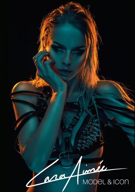 Die Wörter "Cara Aimée MODEL & ICON" sind in Weiß geschrieben. Eine Frau mit Lederoutfit, Nieten und intensivem Licht.