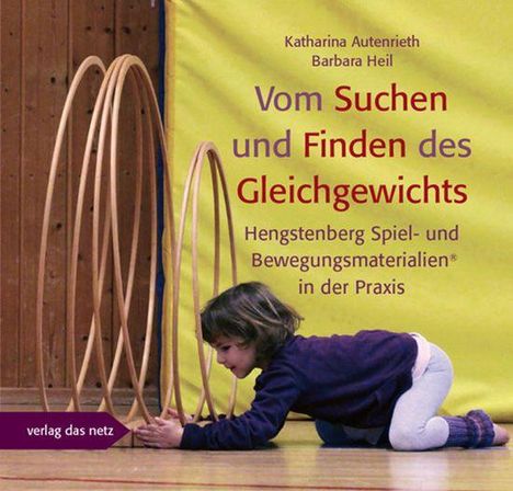 Text: "Vom Suchen und Finden des Gleichgewichts." Ein Kind spielt auf dem Boden mit großen Holzringen in einem Raum.