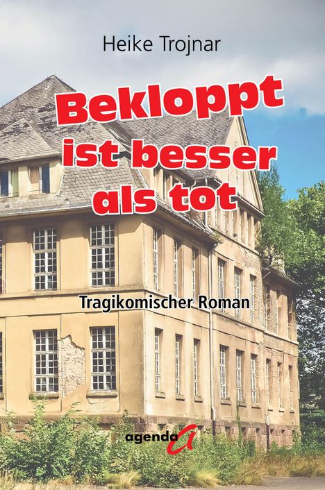 "Bekloppt ist besser als tot" in großer roter Schrift. Ein altes Gebäude mit beschädigtem Putz und Fenstern im Hintergrund.