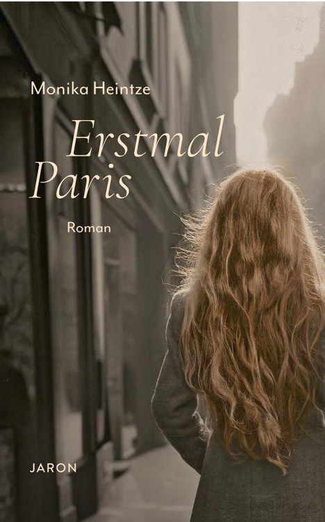 Text: "Monika Heintze, Erstmal Paris, Roman, JARON." Eine Person mit langen Haaren steht in einer städtischen Gasse mit Gebäuden.
