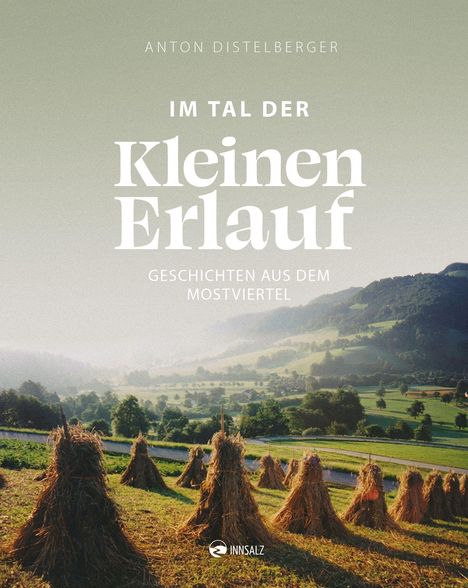 „Anton Distelberger: Im Tal der Kleinen Erlauf - Geschichten aus dem Mostviertel“. Heuhaufen auf grüner Wiese vor Hügeln.