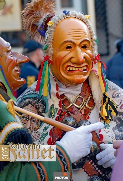 2027 Rottweiler Fasnet. Eine Figur mit bunter Holzmaske und traditioneller Kleidung voller bunter Bänder und Glöckchen.