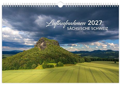 Text: "Luftaufnahmen 2027 Sächsische Schweiz". Eine beeindruckende Felsformation erhebt sich über grünen Feldern unter dramatischem Himmel.