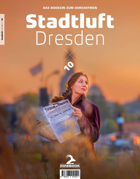 „Stadtluft Dresden“ in großer Schrift oben und „Das Bookzin zum Durchatmen“ darüber. Frau mit Zeitung im Sonnenuntergang.