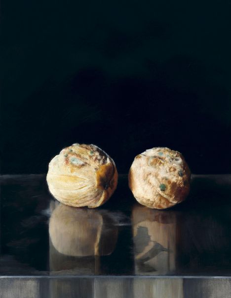 Zwei alte, verschimmelte Brötchen zeigen sich auf einer reflektierenden Oberfläche vor dunklem Hintergrund.