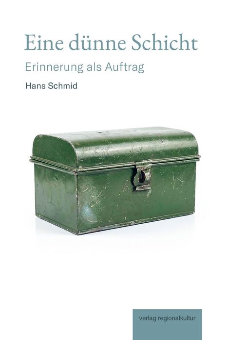 Oben steht "Eine dünne Schicht: Erinnerung als Auftrag" von Hans Schmid. Unten grüne Metallkassette.