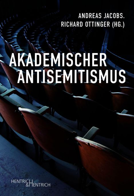 „Andreas Jacobs. Richard Ottinger (Hg.). Akademischer Antisemitismus.“ Holzstühle in einem Vortragssaal.
