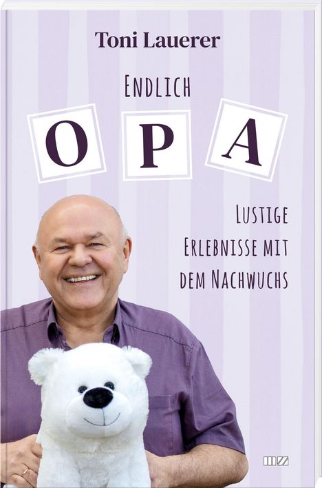 Toni Lauerer, Endlich Opa: Lustige Erlebnisse mit dem Nachwuchs. Ein Mann lächelt, hält einen weißen Plüschbären.