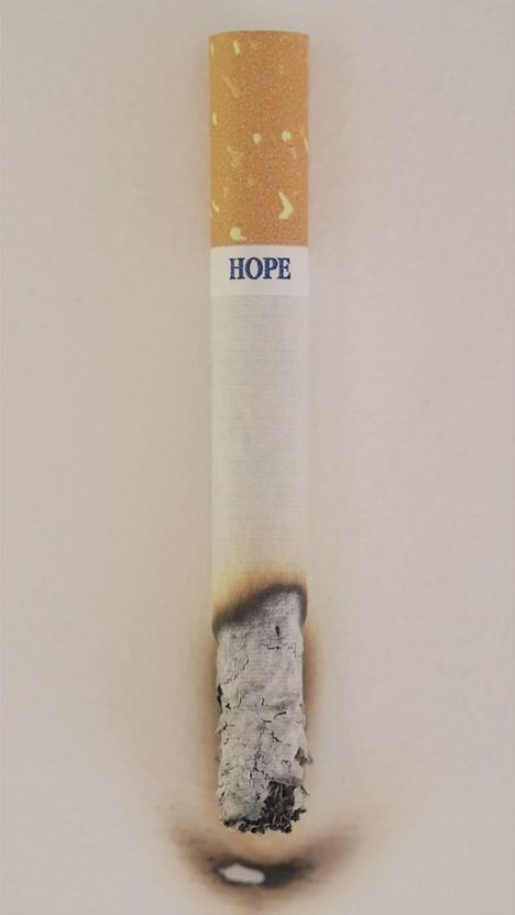 Eine brennende Zigarette, deren Filter die Aufschrift "HOPE" trägt.