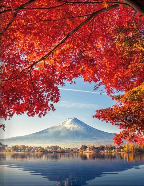 Rotes Herbstlaub rahmt einen schneebedeckten Berg, der sich in einem klaren See spiegelt.
