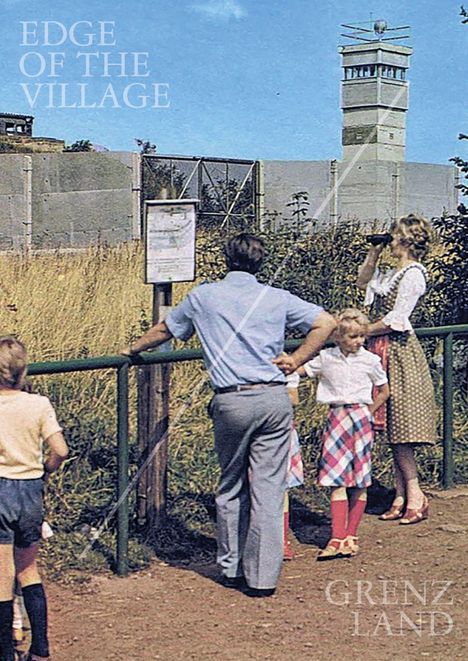 Texte: "EDGE OF THE VILLAGE", "GRENZLAND". Eine Familie beobachtet eine Grenzanlage mit Turm. Frau mit Fernglas.