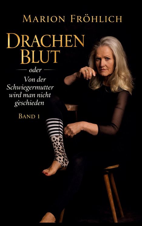 „Marion Fröhlich - Drachenblut oder Von der Schwiegermutter wird man nicht geschieden, Band 1.“ Frau im Stuhl, schwarze Kleidung.