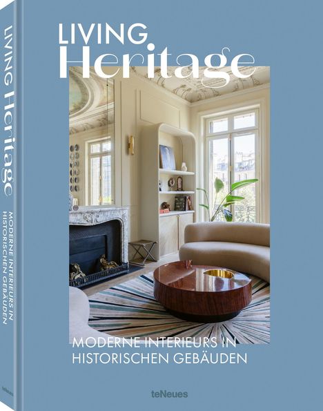 "LIVING Heritage", "MODERNE INTERIEURS IN HISTORISCHEN GEBÄUDEN". Elegantes Zimmer mit Kamin, Sofa, rundem Tisch, Pflanzen.