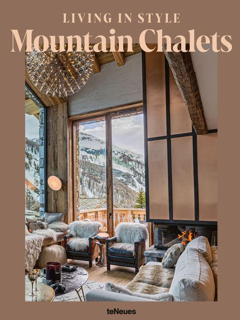 "LIVING IN STYLE Mountain Chalets" in Beige, zeigt ein stilvolles Chalet-Interieur mit Kamin, Fellmöbeln und Bergblick.