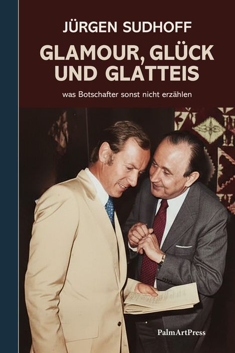 "Jürgen Sudhoff, Glamour, Glück und Glatteis. Zwei Männer in Anzügen interagieren in einem förmlichen Rahmen."