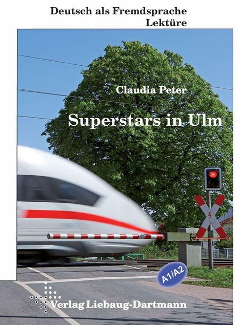 „Superstars in Ulm“ von Claudia Peter. Ein Zug überquert einen Bahnübergang, daneben eine Ampel und ein Baum im Hintergrund.