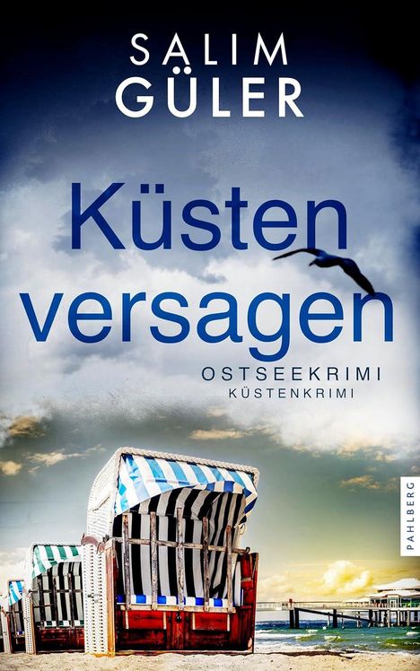 "Küstenversagen. Ostseekrimi. Küstenkrimi. Ein Strandkorb am sandigen Strand mit einem Steg und Wolken im Hintergrund."