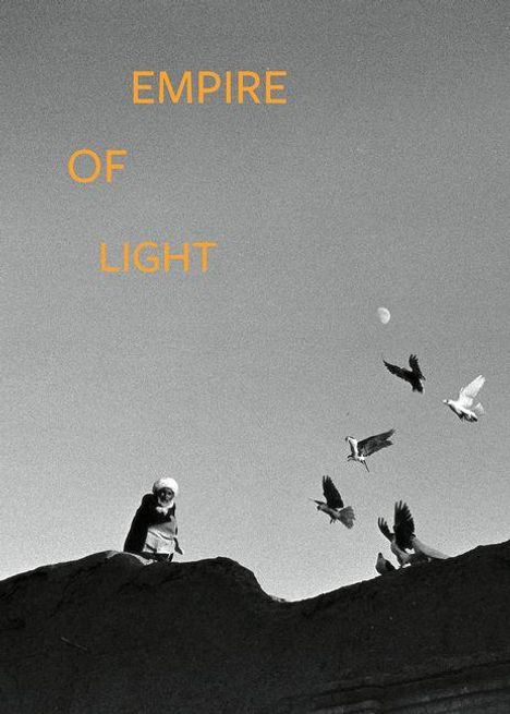 Text: "EMPIRE OF LIGHT". Eine Person steht mit Vögeln umgeben auf einem Dach, der Himmel ist klar mit einem Mond im Hintergrund.