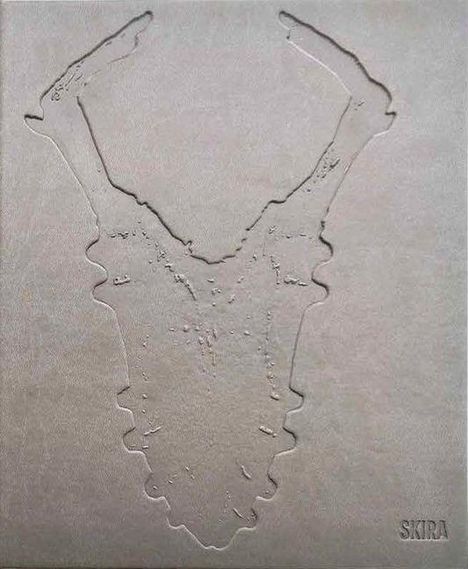 Text: SKIRA. Geprägtes Muster in Form eines stilisierten Schädels, auf grauem Hintergrund.