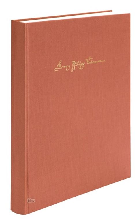 Goldener handschriftlicher Text auf rotem Buchdeckel, stehendes Buch mit mattem Einband.