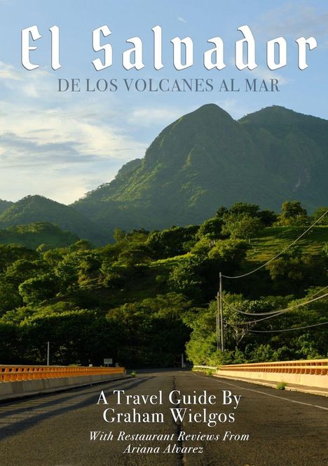 "El Salvador: De los volcanes al mar. Ein Reiseführer von Graham Wielgos mit Restaurantkritiken von Ariana Alvarez." Im Hintergrund grüne Berge und eine Straße.