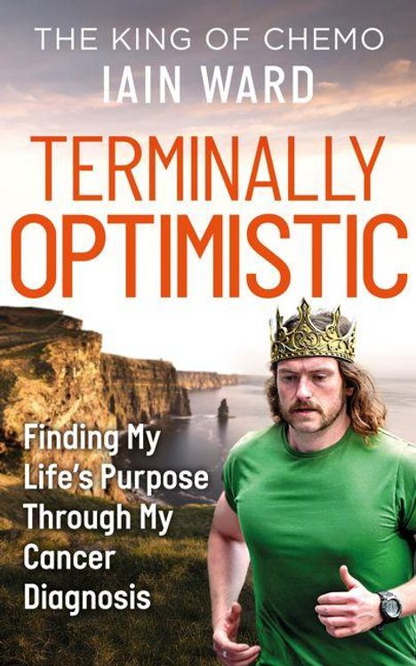 „The King of Chemo“ Iain Ward „Terminally Optimistic“. Mann in grünem Shirt und Krone, läuft vor Klippenlandschaft.