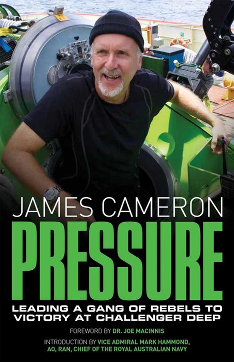 JAMES CAMERON PRESSURE; Mann in schwarzem Shirt und Mütze lacht in einer technischen Umgebung.