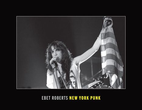 "EBET ROBERTS NEW YORK PUNK" steht unten. Eine Person singt mit Mikrofon und hält eine flaggenähnliche Stoffbahn hoch.
