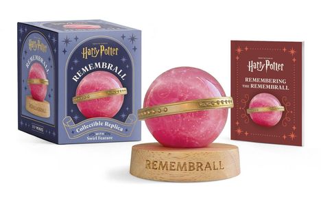 "Harry Potter Remembrall", blaue Verpackung, rote Kugel mit goldenem Ring auf Holzständer, daneben rotes Buch.