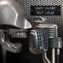 Text: "Gary Klebe Out Loud". Zwei Retro-Mikrofone und ein metallischer Schädel auf perforierter Metalloberfläche.