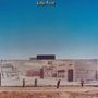 Text: "Little Feat". Eine Wand zeigt ein Wandgemälde eines Supermarkts, davor stehen fünf Menschen, blauer Himmel im Hintergrund.