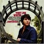 "TONY JOE WHITE ...CONTINUED." Ein Mann in dunklem Hemd steht vor einem dekorativen Metallbogen.