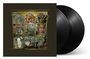 Ein kunstvolles Regal mit verschiedenen Objekten, wie Instrumenten, Pflanzen und Statuen. Daneben zwei schwarze Vinyl-Schallplatten.