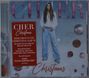 Rotes Textfeld: "CHER Christmas." Cher in weißem Hemd, blauen Jeans. Hintergrund: Kugeln und "Christmas" am Ende.