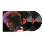 Text: "BOB DYLAN AT BUDOKAN". Zwei Schallplatten, ein Porträt eines Mannes mit lockigem Haar in farbigem Licht.