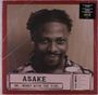 ASAKE, MR. MONEY WITH THE VIBE. Schwarz-weiß Foto eines lächelnden Mannes mit Frisuren in einem rot umrandeten Rahmen.