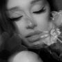 Keine Texte sichtbar. Schwarz-weiß Porträt einer Frau mit geschlossenen Augen, umgeben von Blumen.
