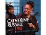 „Catherine Russell Live @ Jazz at Lincoln Center“. Eine Frau singt lächelnd mit Mikrofon, ein Musiker im Hintergrund.