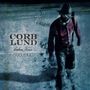 "Corb Lund Cabin Fever Deluxe." Ein Mann in rotem Hemd und Hut läuft durch Schnee mit Fußabdrücken.