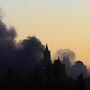 Dunkler Rauch steigt über einer Stadtsilhouette in den Abendhimmel.