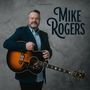 Der Text "Mike Rogers" ist groß. Ein Mann im Anzug hält eine akustische Gitarre vor einem neutralen Hintergrund.