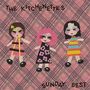 "The Kitchenettes" oben, "Sunday Best" unten. Drei stilisierte Figuren in bunten Kleidern vor einem rosa karierten Hintergrund.