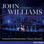 „JOHN WILLIAMS: A Tribute to“. Orchester auf einer Bühne, blaue Beleuchtung, Publikum im Vordergrund.