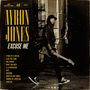 Große Schrift: AYRON JONES. Weitere Texte: EXCUSE ME, Strike of a Match, Glad You Came. Person mit Gitarre in einer Gasse.