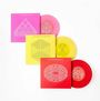 Drei bunte Schallplattenhüllen mit geometrischen Mustern: eine pink, eine gelb und eine rot.
